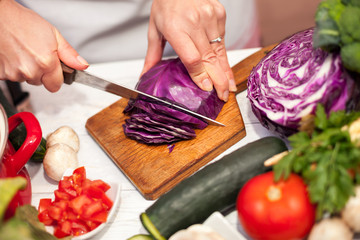 Woman slicing red cabbage on slices in the kitchen
