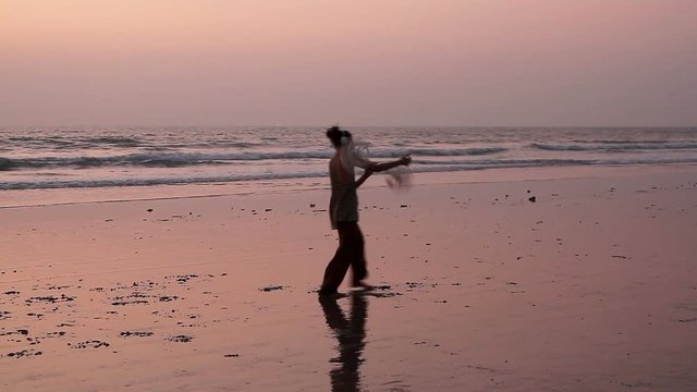 Unidentified man spinning pole on the beach. 