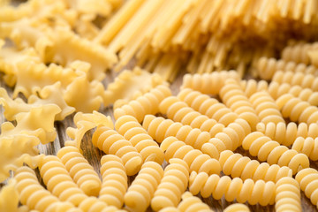 Variety of types and shapes of dry Italian pasta. Italian Macaroni raw food background/texture: spaghetti , pasta in shape of spiral .Raw spaghetti wallpaper. Thin spaghetti. Food background concept