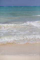 Fototapeta na wymiar Waves hitting the beach. White sand beach with turquoise sea water.