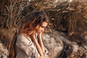 attractive young barefooted girl sitting on stone at sunset