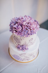Violet flowers on the top of white tired cake