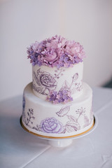 Violet flowers on the top of white tired cake