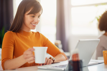 Young beautiful woman working in modern office sitting at the table with laptop
