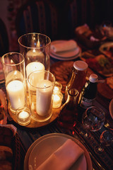 Glass vases with shiny candles stand on wooden block