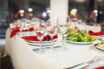 Three glasses stand by white plate with red napkins