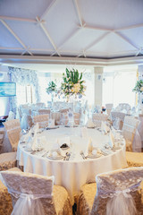 Beige chairs stand at white dinner table in cosy restaurant hall