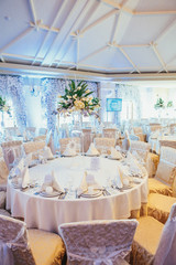 Beige chairs stand at white dinner table in cosy restaurant hall