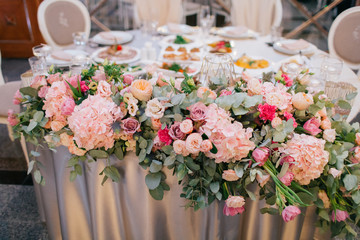 Garland of pink roses and hydrangeas lies on table covered with silk
