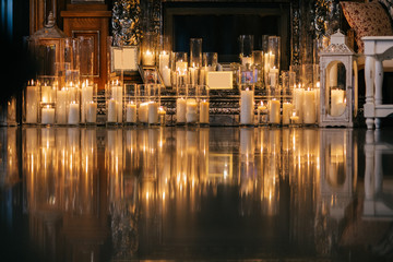 Shiny candles stand on marble floor