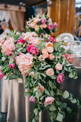 Garland of pink flowers and greenery lies on table with silk cloth