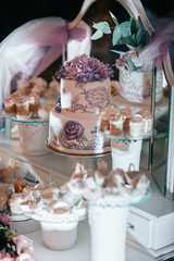 Tired violet cake stands among other sweets on the table