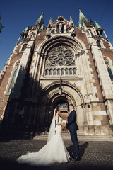 Bride and groom look in each other eyes standing before Gothic church