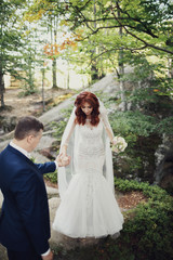 Obraz na płótnie Canvas Groom helps bride to step out of the rock