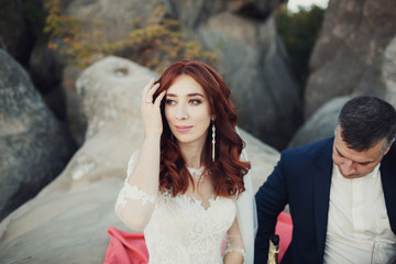 Bride fixes her hair sitting on the rocks