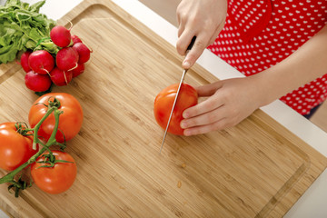 Cutting tomatoes with knife in the kitchen.