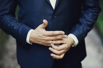 Groom fixes golden wedding ring on his finger