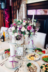 The vase with flowers and frame with number standing on the table