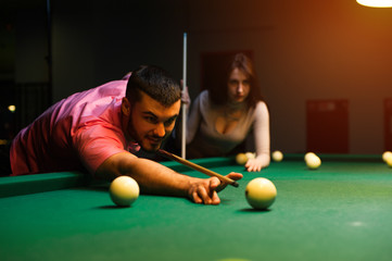 Romantic couple having fun playing billiard game