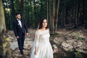 The charming brides walking along forest