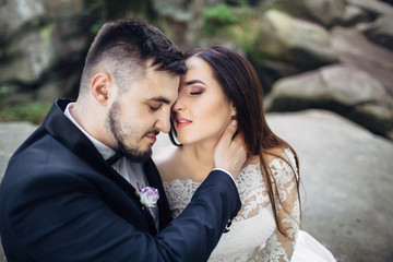 The lovely couple in love sitting on the stones