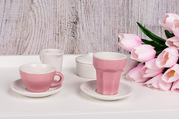 Taza de café, vaso y tulipanes en bandeja blanca.