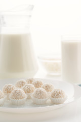 Raffaello candy in baskets on a plate, with milk in a glass and jug, cottage cheese in a bowl in...