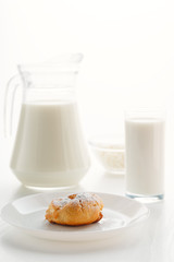 Eclair cake in a plate, with milk in a glass and jug, cottage cheese in a bowl in the background, on a white table, in a high key, with space for text