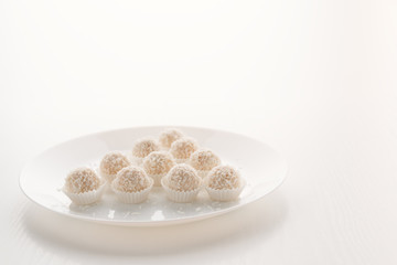 Raffaello candy in baskets on a plate, on a white table, in a high key, with space for text