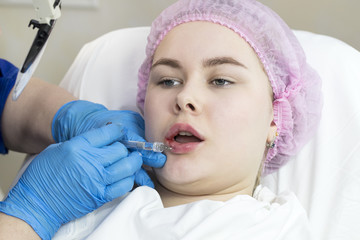The process of cosmetic surgery of water injection in the area of the lips of a woman 