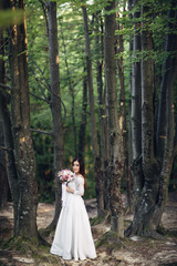 The charming bride stands near trees