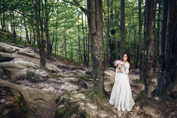 The charming bride stands near trees