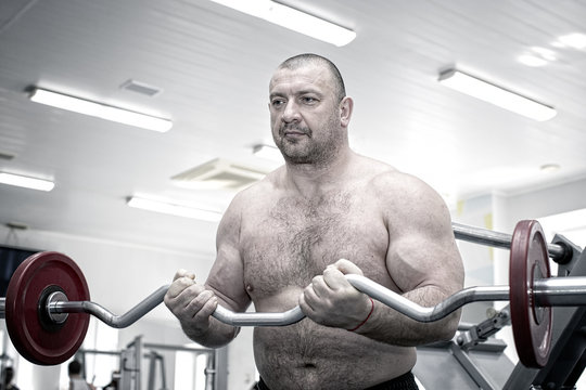 The adult brutal man is engaged in power bodybuilding in the gym 