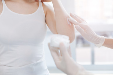 Professional dermatologist putting medical cream on patient skin at work