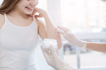 Professional practitioner testing new medical cream on patient skin at work