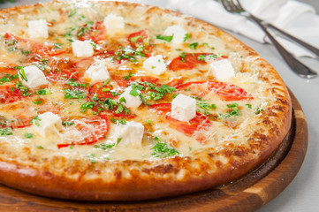 Four cheese pizza quattro fromaggi on a rustic wooden board on the table with ingridients. Selective fovus