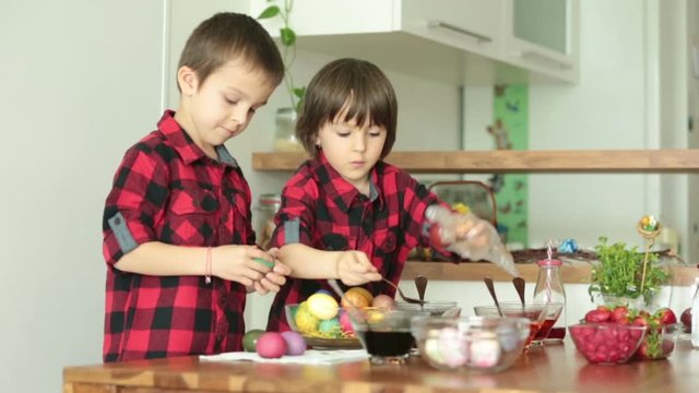 Two children, boys, coloring easter eggs at home