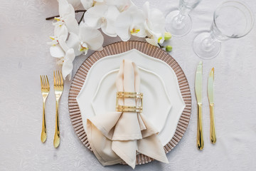 White orchid hangs over pink and white dinner plates