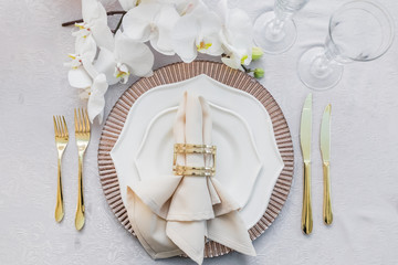 White orchid lies before pink and white dinner plates