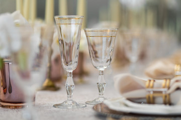 Crystal glasses with golden design stand on dinner table