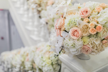 Little vase with beige and white roses on white handrails