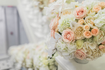 Little vase with beige and white roses on white handrails