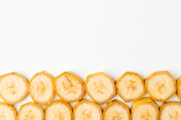 Background of sliced banana slices from below into a row on a white table with space for text