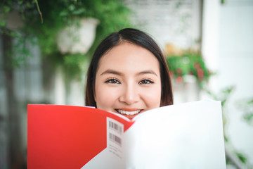 Portrait of young asian woman reading book at home