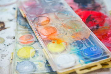 Paintbrush palette. Palette of watercolor paints on abstract background, close up.