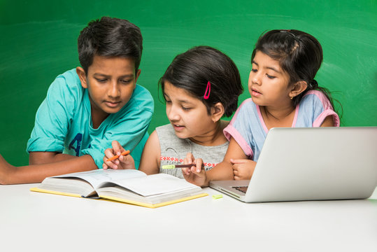 indian school kids using laptop in a classroom over green chalkboard background with doodles