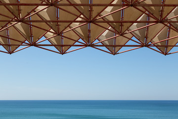 Abstract iron construction and blue sea, no clouds. Background with the sea view.