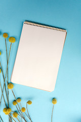 Notebook mock up for artwork with yellow flowers on turquoise background. View from above.