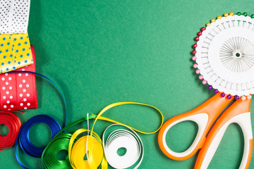 Fototapeta premium Scissors, pins and color tapes on green background