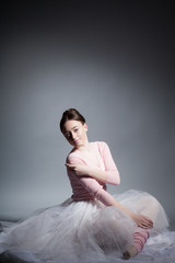 Fototapeta premium Beautiful girl ballerina on a gray background in the studio